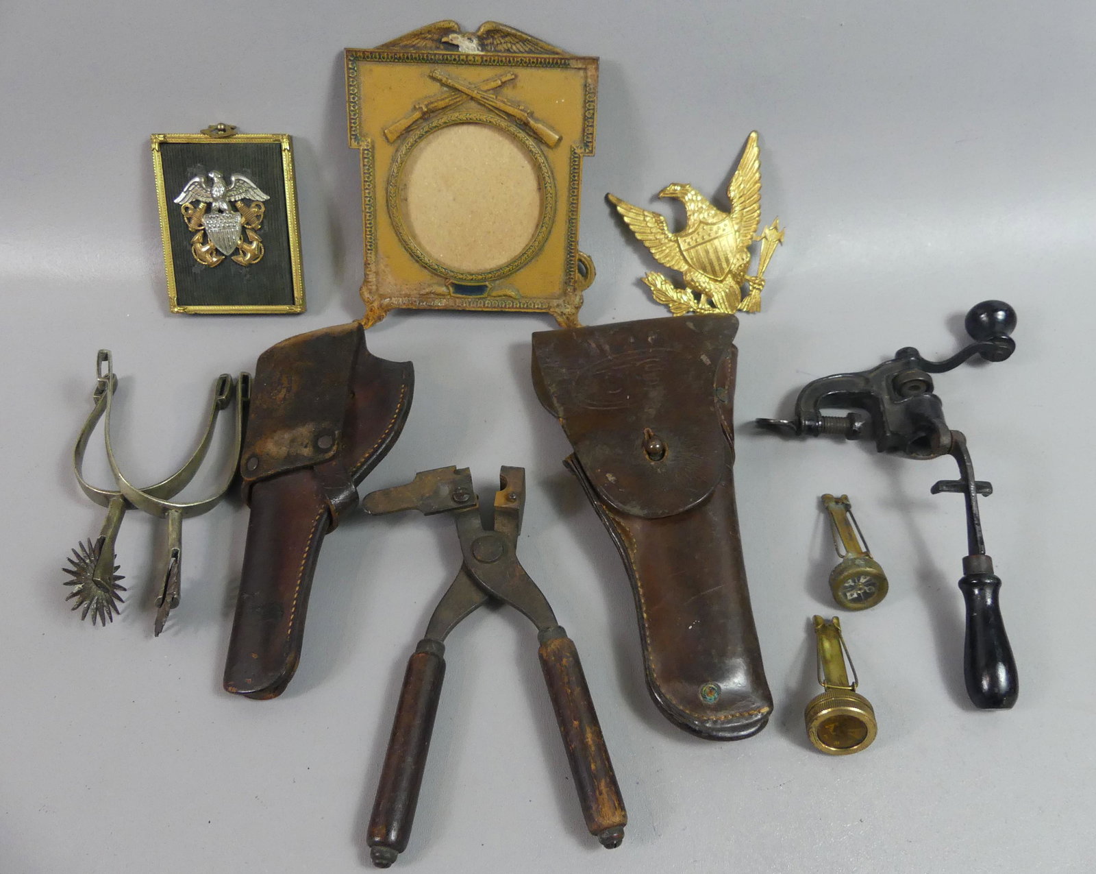 LOT OLD MILITARY ITEMS & HOLSTERS: Lot Spanish-American and WWI era items: 2 leather gun holsters; pair spurs; 2 small compasses; bullet molds; iron picture frame with eagle & rifles, 7 in tall.