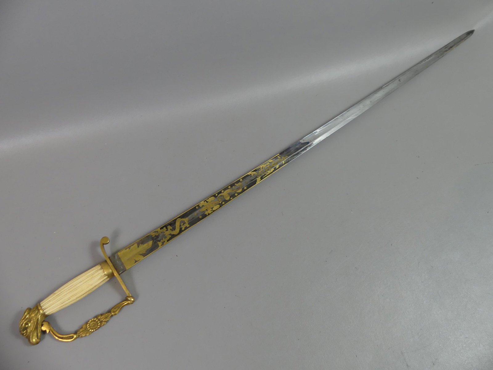 CA 1830 EAGLE POMMEL SWORD: Fine American eagle pommel militia sword with brass hand guard and ribbed bone grip circa 1830. Fancy etched, blued and gilt blade with E. PLURIBUS UNUM and WARRANTED. 38 in overall, 32.75 in blade.