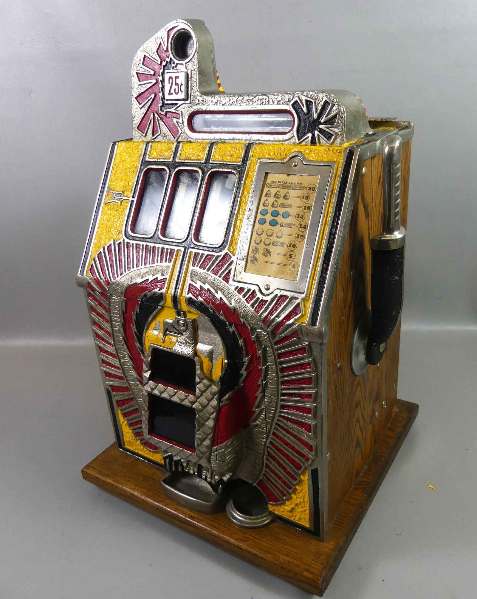 ART DECO MILLS 25C SLOT MACHINE: Art Deco era, oak and painted metal 25 cent slot machine by Mills of Chicago. Has embossed Native American eagle on front, 3 Bell-Fruit Gum wheels. Appears complete, good cosmetic condition, not curre