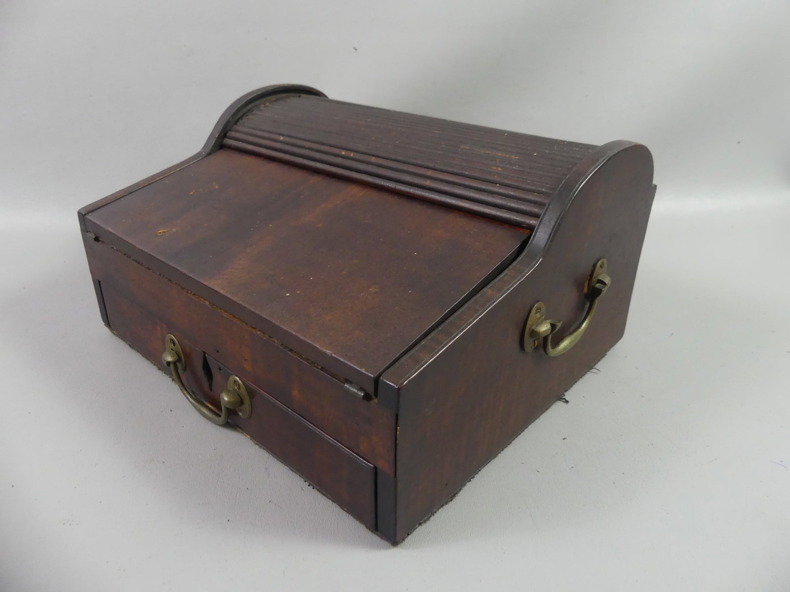 ANTIQUE TAMBOUR PORTABLE DESK: 19th century lap desk with tambour sliding top revealing 3 inkwells and interior drop-down writing surface, below which are 3 small drawers. When the exterior drawer is opened the tambour top rolls ba