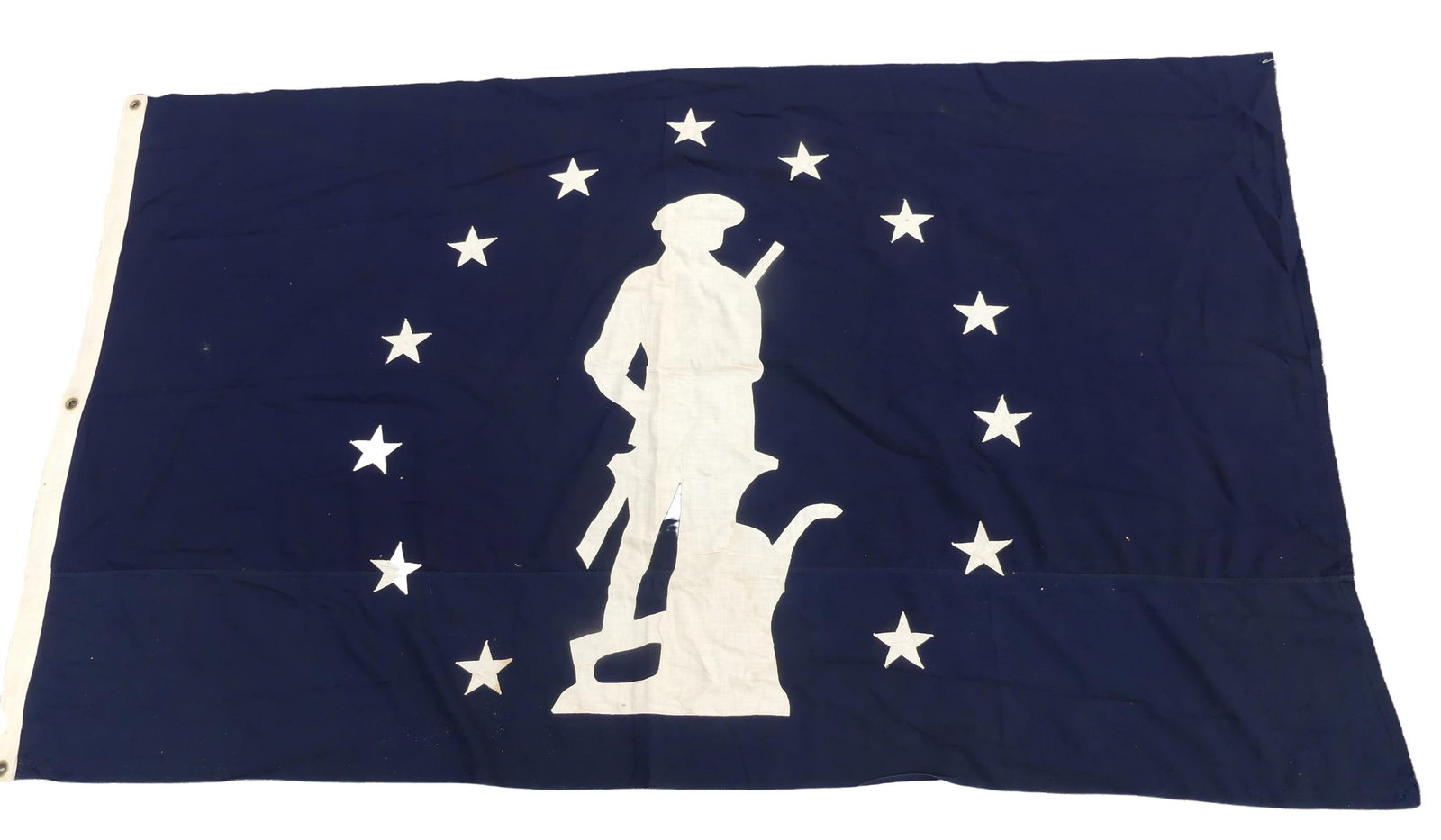 MASS. MINUTEMAN FLAG: Old cotton blue and white double-sided flag with 13 stars surrounding the Massachusetts Minuteman logo. 69 x 42 inches. Few minor stains.