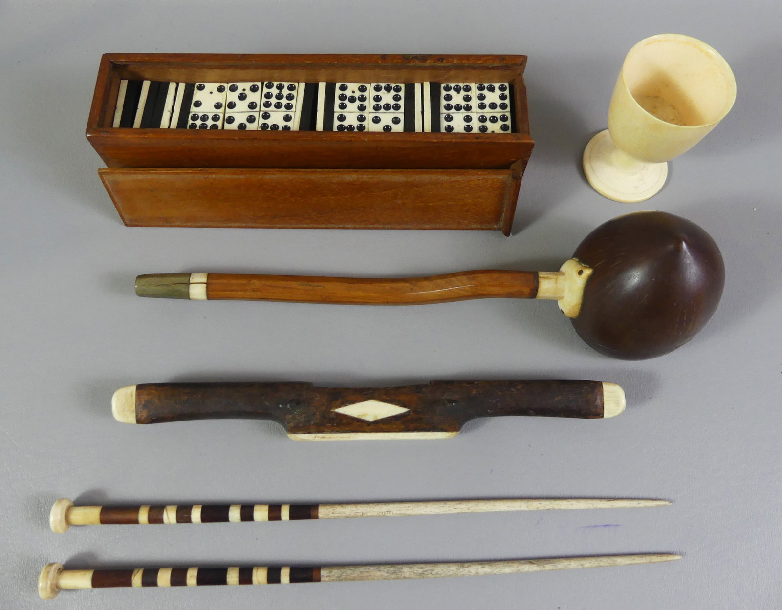 6 PC. WHALE BONE LOT - DOMINOES ETC.: 6 pc 19th century whale bone lot including set of dominoes in wood case; footed cup, 3.5 in; 13 in coconut dipper; 2 sail needles; and spoke shave tool.