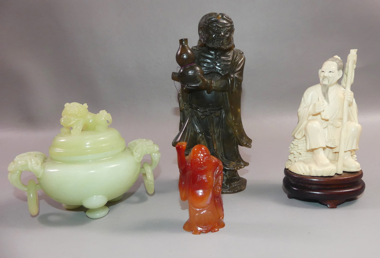 LOT OF 4 FIGURAL CARVED ASIAN PIECES: Lot of 4 old/antique Asian items: 5 in Chinese carved bone figure of man smoking; 6.75 in dark green carved stone figure of a man holding gourd; 2.5 in figurine in carnelian agate of a man with proven