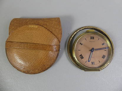 CARTIER TRAVEL CLOCK: Old Cartier brass portable 8 day manual wind clock in leather pouch, 2.5 in (63.5mm) diameter. Has folding ring stand. Back engraved BO de Z. Currently running.