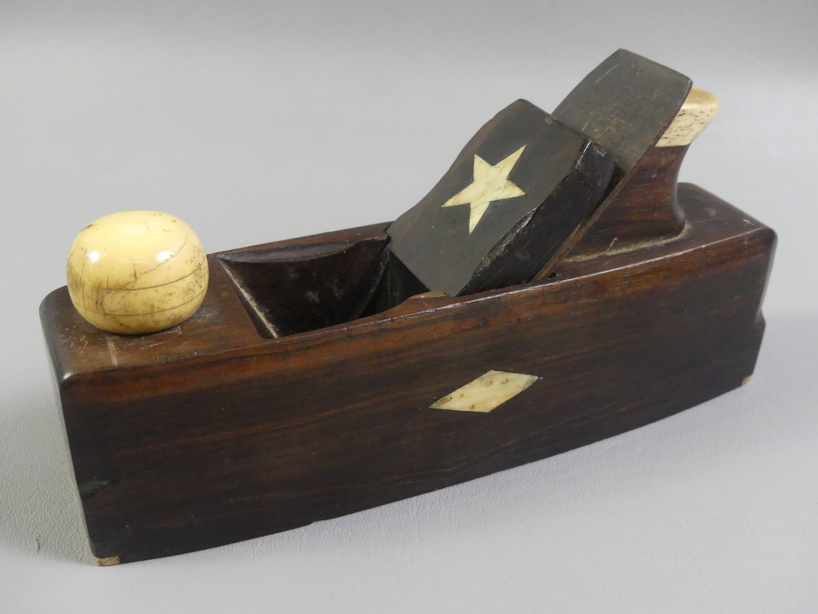 BONE INLAID ROSEWOOD PLANE: Fine 19th century solid rosewood sailor-made plane tool with whalebone inlay of star and diamonds. Blade stamped with maker name? 8.75 x 4 x 2.25 in.