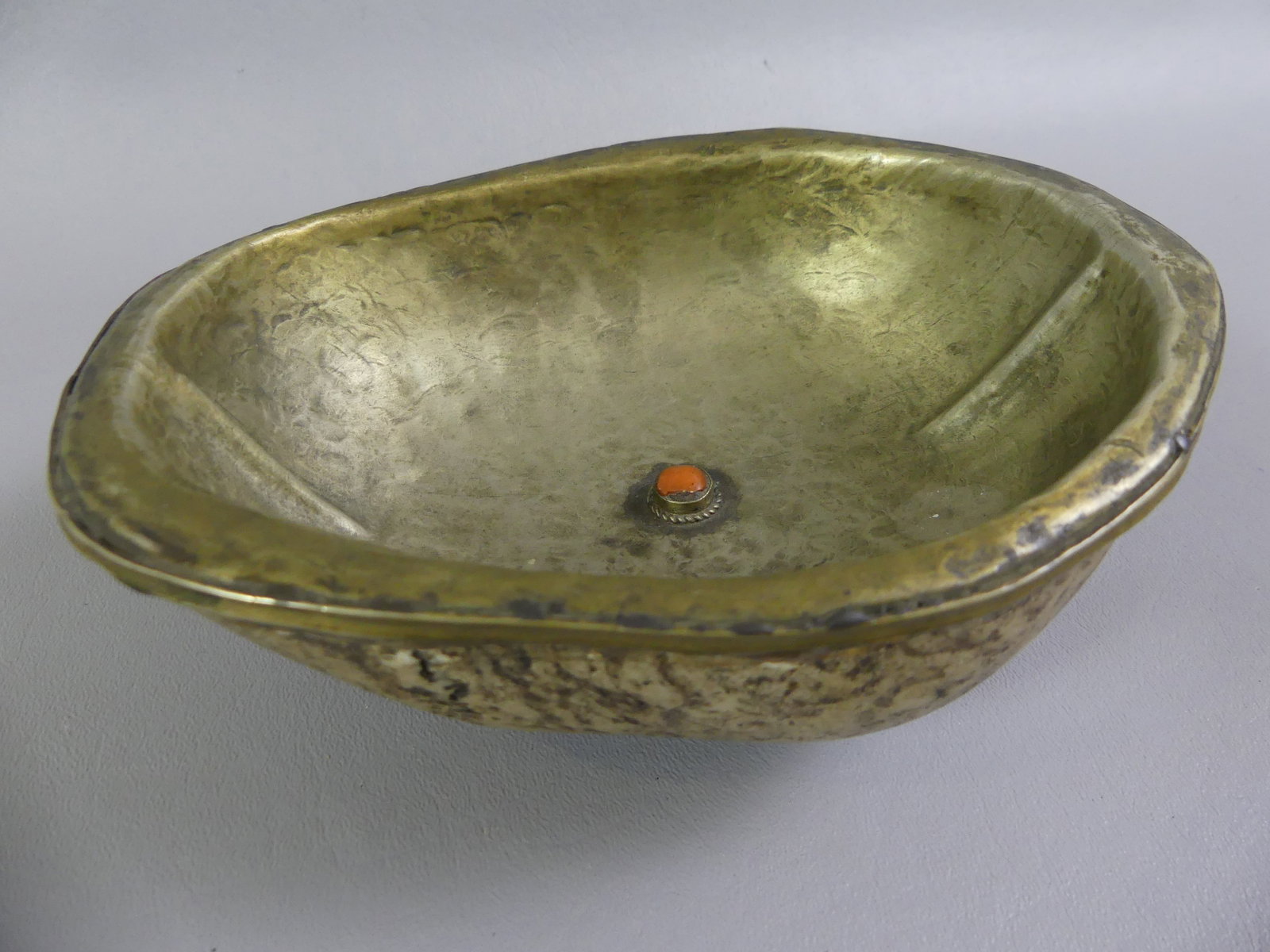 ANTIQUE JEWELED KAPALA BOWL: Antique Tibetan Kapala, a human skull cap ritual bowl encased in silver and metals with center coral jewel. Size: 7 x 5.5 in. NOTE: A Sanskrit term meaning ?skull,? the kapala incorporates a human sku