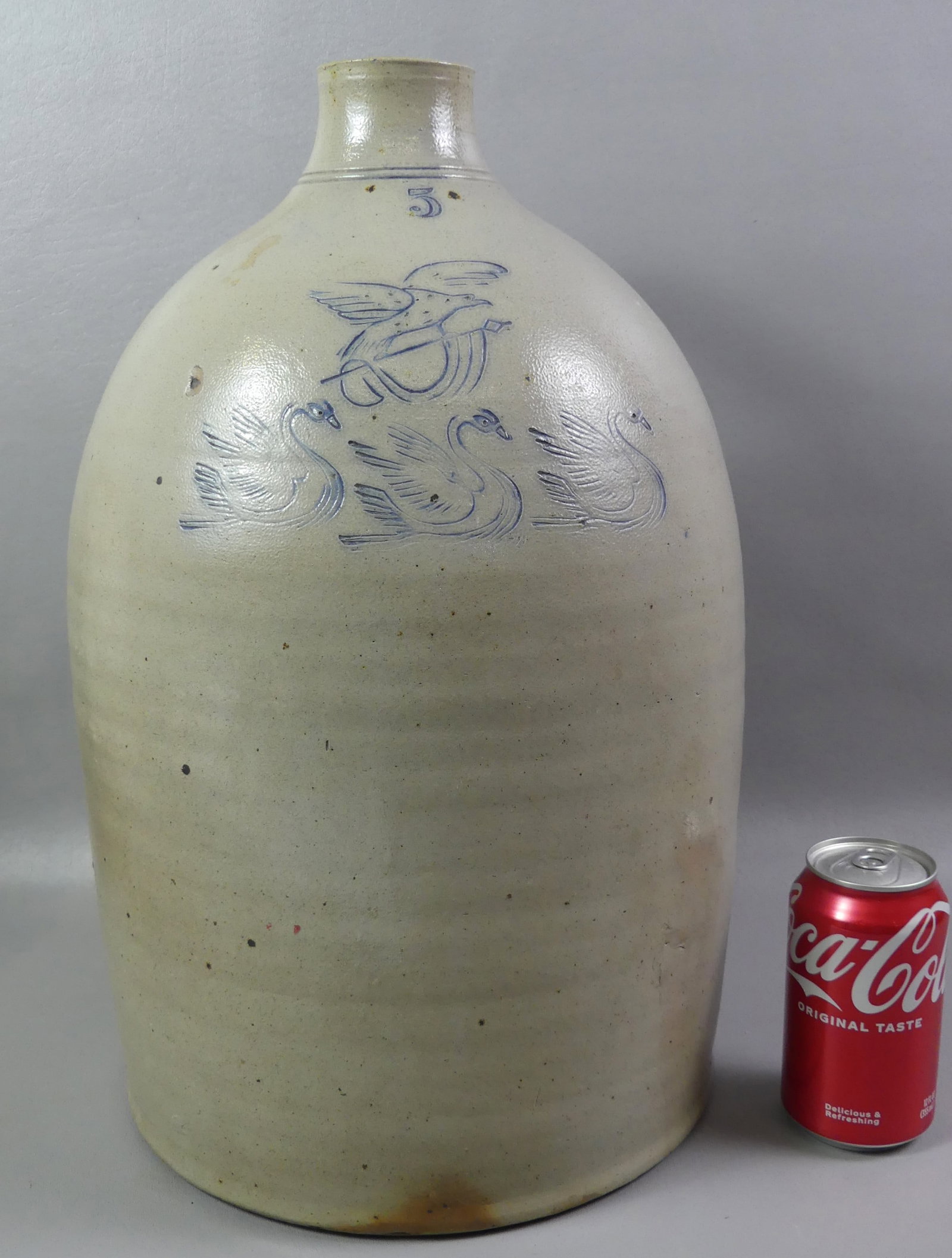 ANTIQUE STONEWARE JUG WITH EAGLE & SWANS DECORATION: Antique stoneware #5 jug with blue incised decoration of American eagle on flag and 3 swans, 18 in tall. Good condtion.