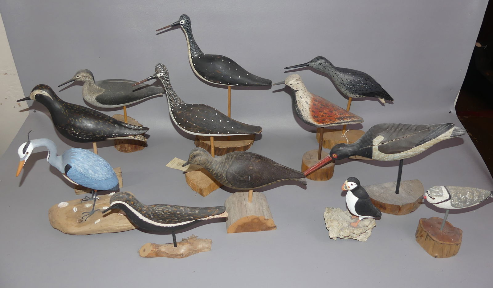 12 CARVED SHORE BIRDS: Lot 12 assorted carved wood shore birds to 15 in tall including 5 signed WEK (Will Kirkpatrick of Hudson MA); Blue Heron signed Polly M. Root (VT); Unsigned puffin; and red back stamped AK. Some unsig