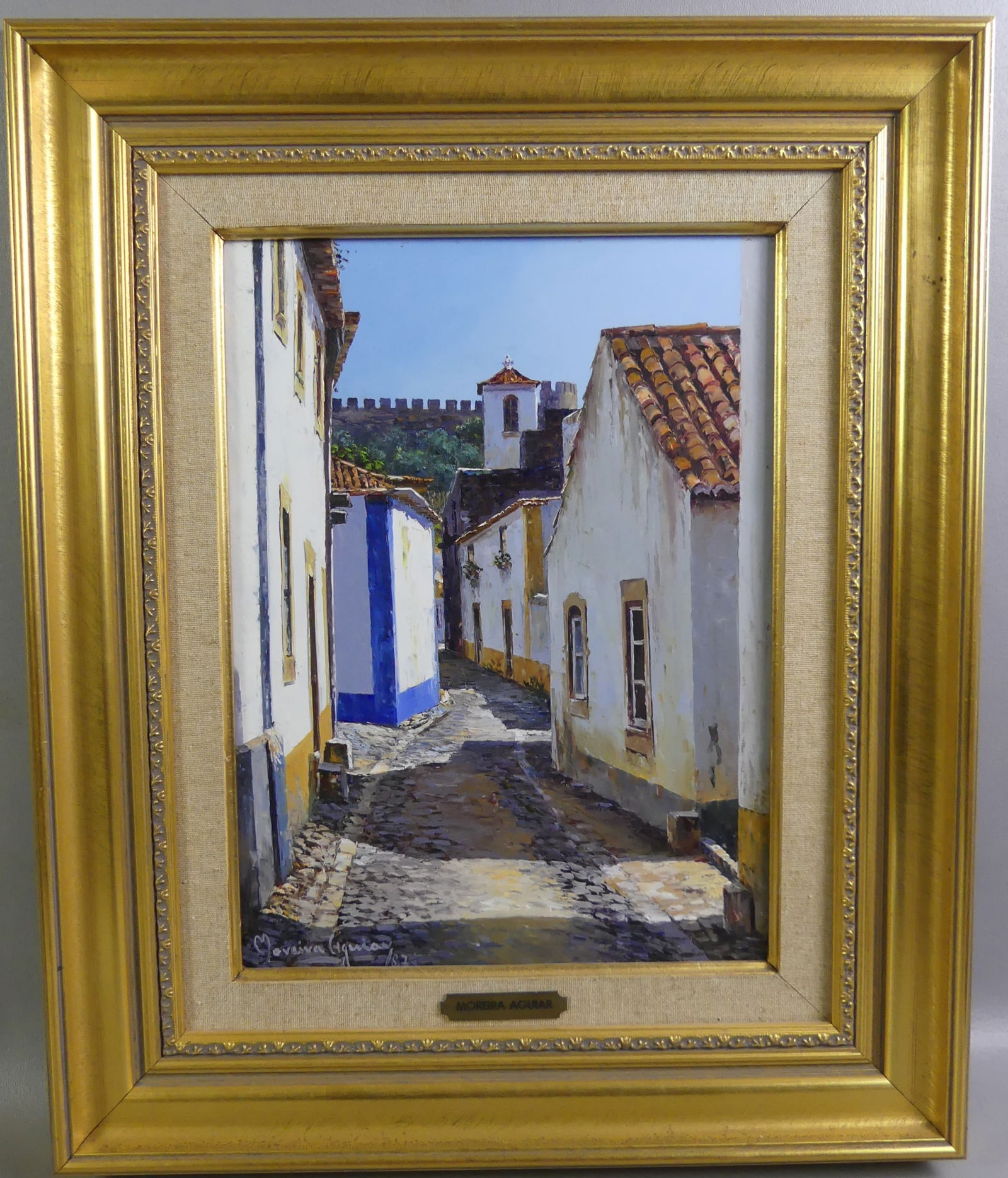 MOREIRA AGUIAR PAINTING - OBIDOS: Oil painting on masonite of a Portuguese village street scene signed M. Moreira and titled verso --Obidos 1987. Size: 15.5 x 12 in, framed 24 x 20. (Moreira Aguiar b. 1947)
