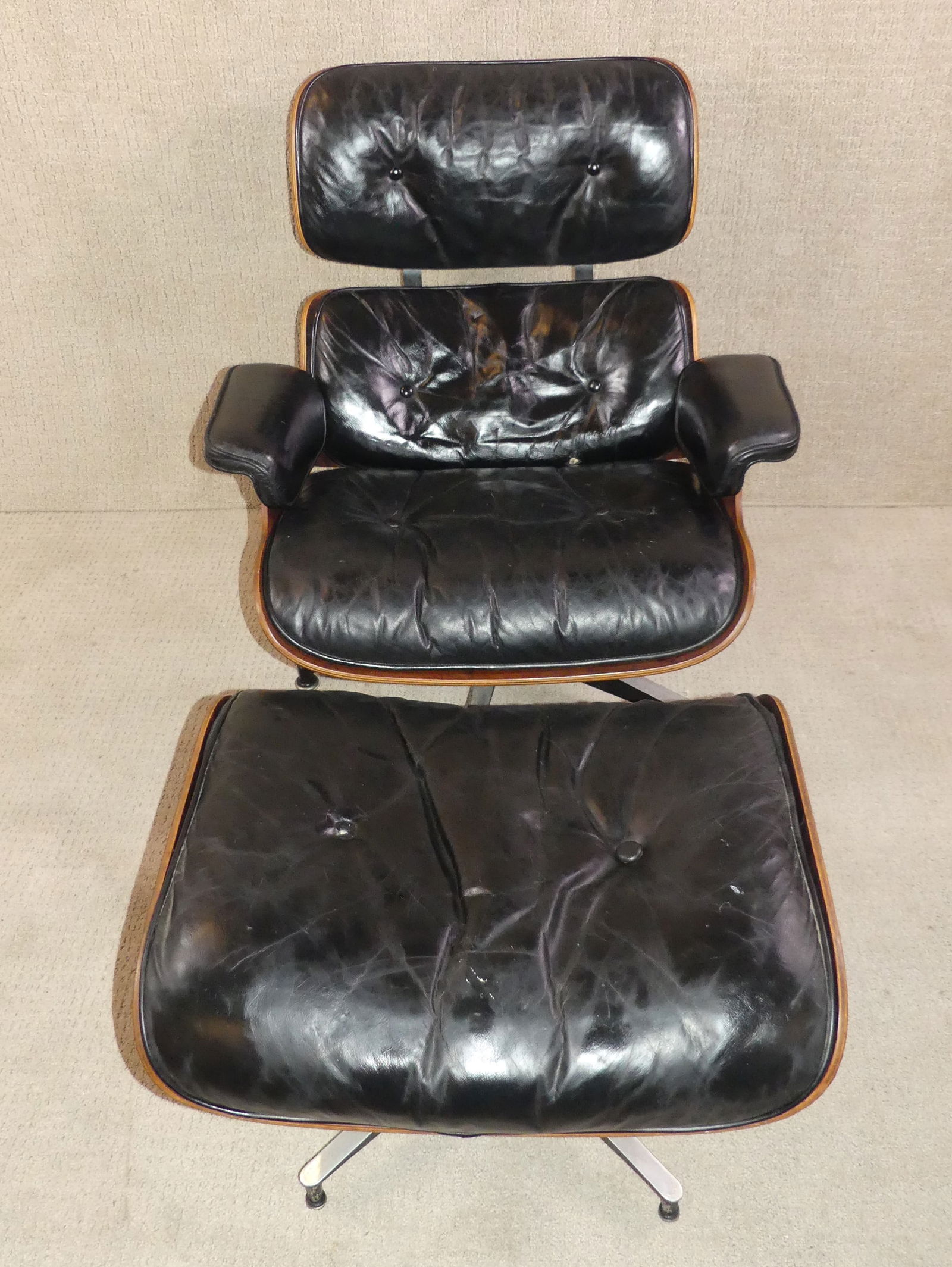EAMES / MILLER LOUNGE CHAIR & OTTOMAN: Mid century Herman Miller lounge chair (model 670) and matching ottoman (model 671) after an iconic design by Charles Eames. Rosewood construction with black leather upholstery. Chair is 32.5 in w x 3