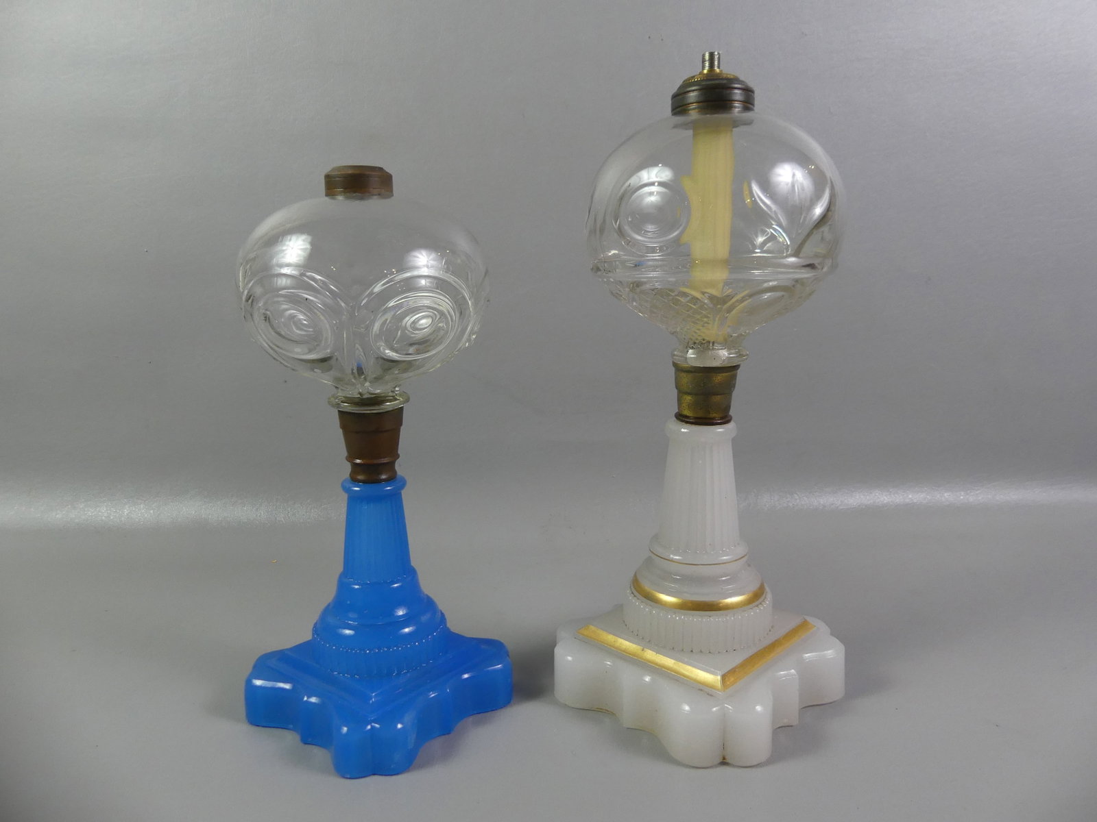 2 ANTIQUE CUT GLASS OIL LAMPS: Lot of 2 antique cut glass oil lamps to 14 in tall: clambroth with clear font (crack) and blue opal base with clear font.