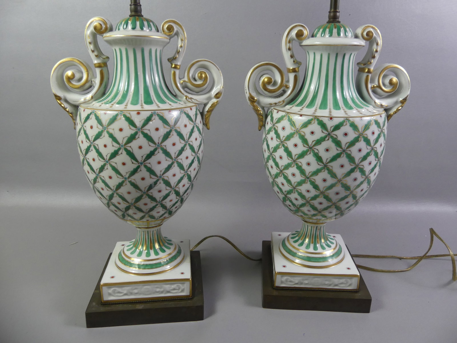 PAIR OLD PARIS PORCELAIN LAMPS: Pair of old Paris porcelain urn-form lamps with green and gold painted decoration with shades. Base 17 in, overall 28 in. One lamp has repairs.
