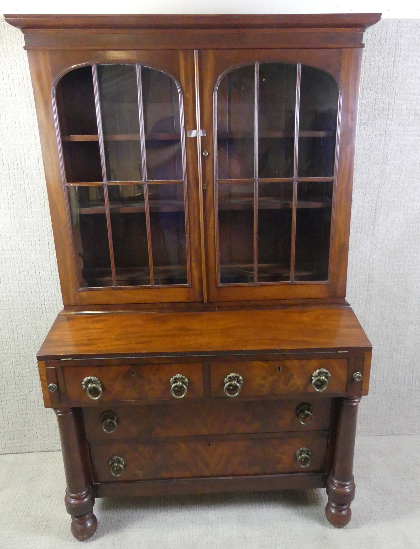 EMPIRE MAHOGANY SECRETARY: Circa 1830 Federal/Empire transitional mahogany secretary desk with 4 drawers and upper glass arched door compartment with shelves and 3 small drawers. Missing one glass pane with 2 others having crac