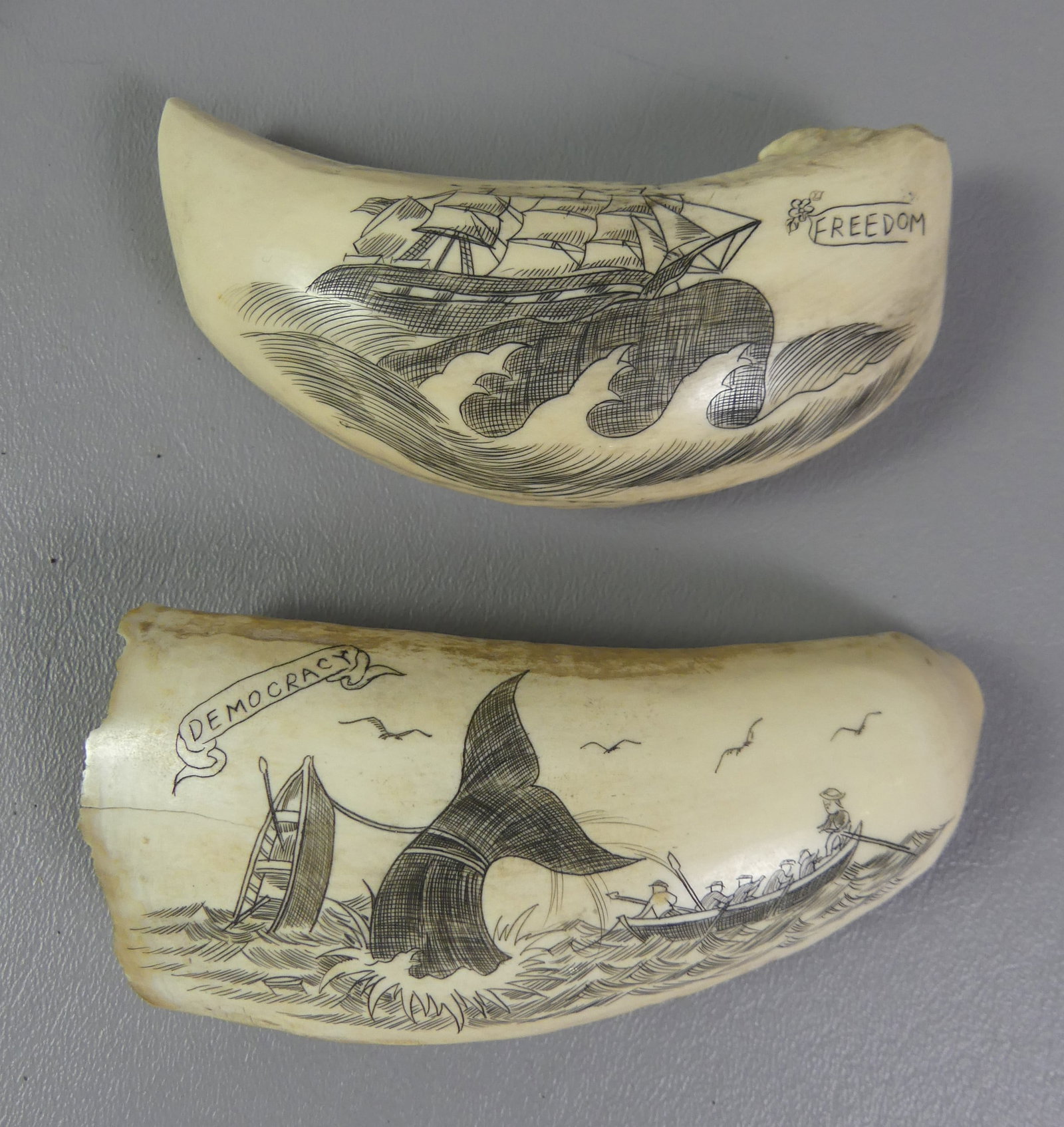 2 SCRIMSHAW WHALE TEETH: Two scrimshaw whales teeth: Whaling scene DEMOCRACY 5 x 2 in, weighs 6.97 oz; and whale ship FREEDOM 4.5 x 1.75 in, weighs 7.72 oz.