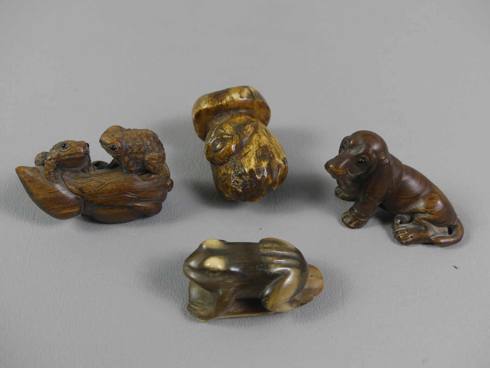 4 OLD JAPANESE NETSUKES: Lot 4 old carved Asian netsukes to 2 in tall: wood basset hound dog, signed; wood of two frogs on lily pad; carved bone mushroom and snail; frog made of horn or antler.
