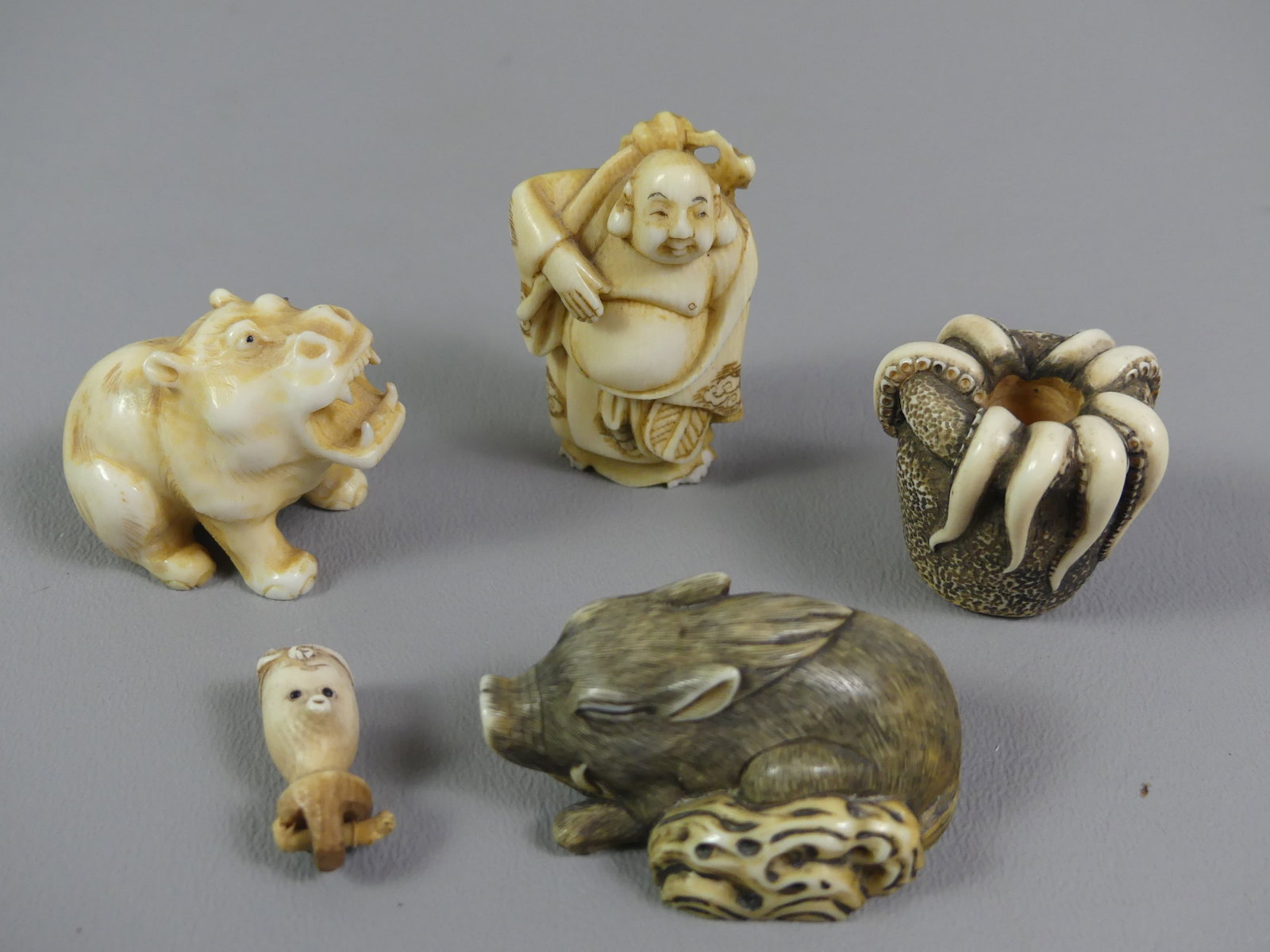4 OLD JAPANESE NETSUKES: Lot 4 old carved bone Asian netsukes, most signed, to 2 in tall: boar, hippo, octopus in pot, figure of Asian man (chips to base) and a tiny 1" head of an octopus.