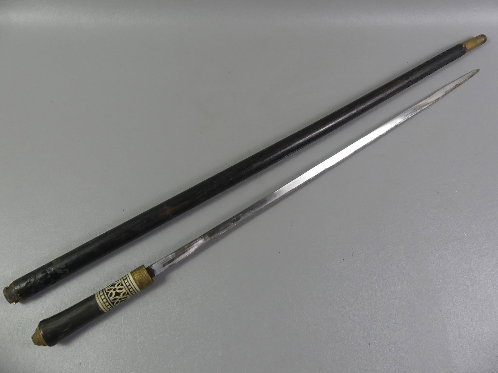 CARVED BONE ASIAN SWORD CANE: Old wood, brass and carved bone Asian sword cane. Blade 23.5 in, overall 35.5 in.