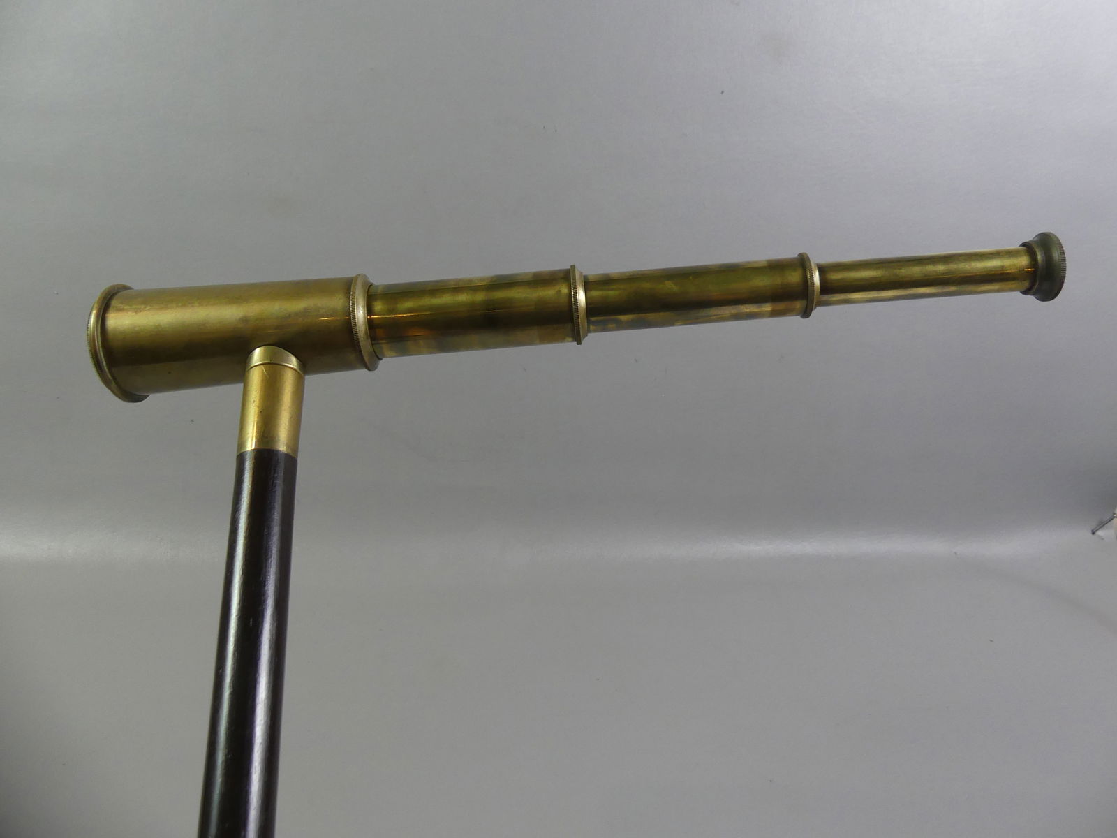 ANTIQUE BRASS TELESCOPE CANE: Fine antique brass telescope cane signed Thomas J. Evans, London. It is a 3 draw scope with 1.25 inch lens and slides from 5.5 inches to 16 in long. Has a 2 section wood and brass shaft. Good conditio