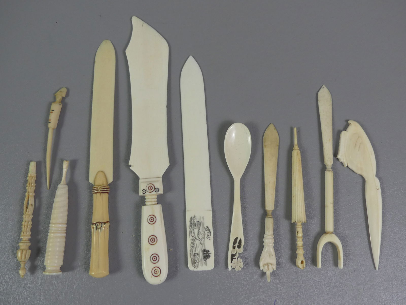 11 CARVED WHALE BONE ITEMS: Lot assorted carved whale bone items, 11 in total: Scrimshaw letter openers (6); needle cases (2); spoon, etc.