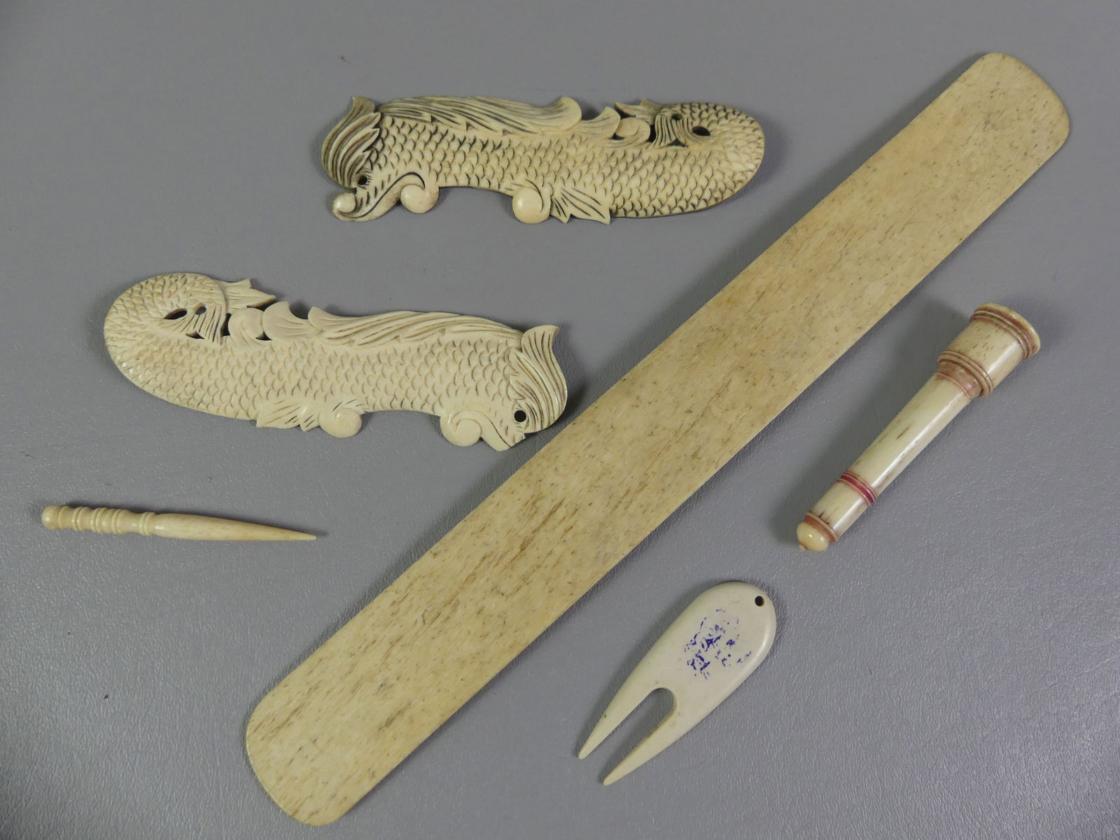 6 PIECES OF CARVED WHALEBONE: Lot 6 pieces of carved 19th century whalebone: 13 in busk, 3.5 in needle case, pair of 5.5 inch dolphin plaques, etc.