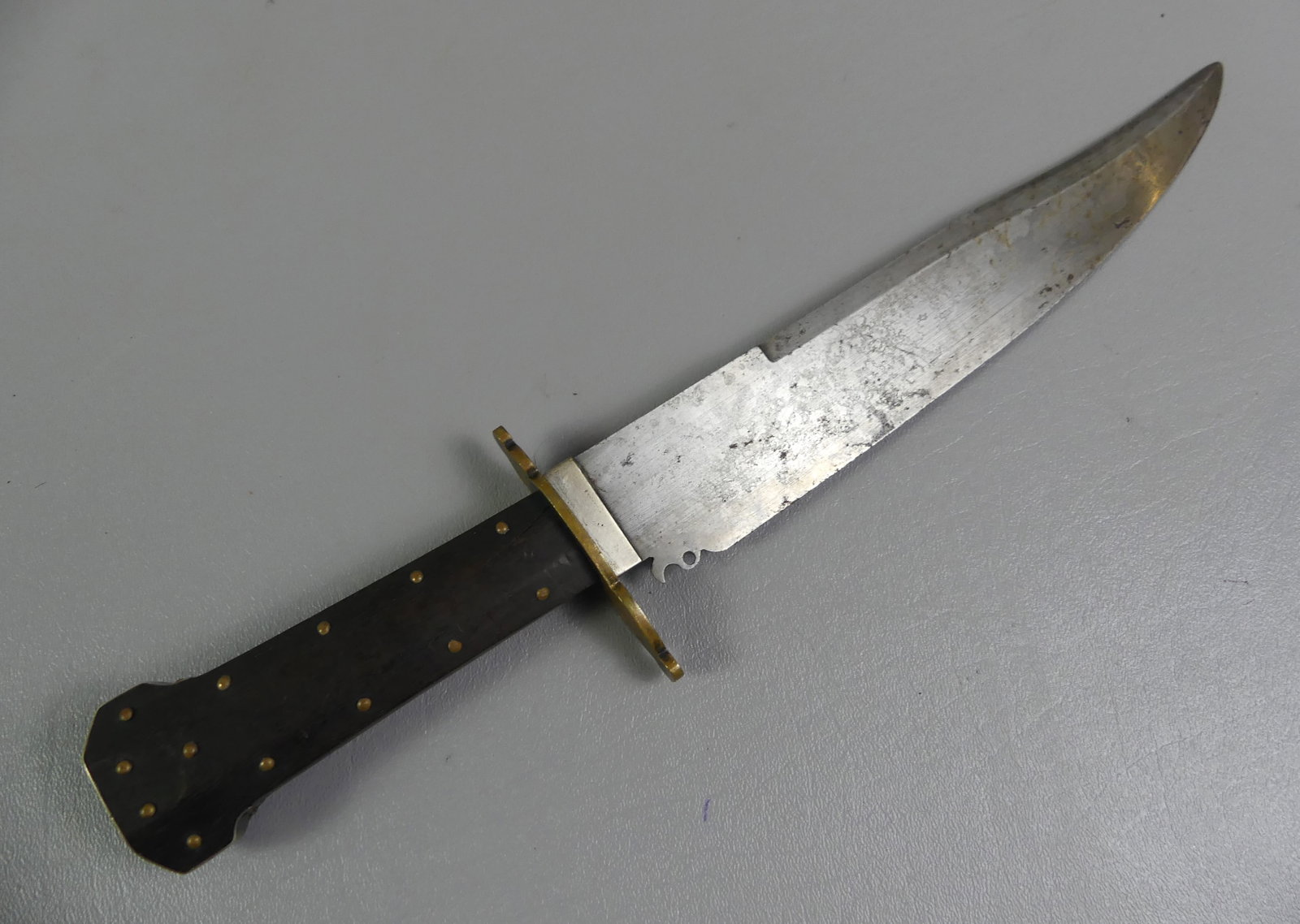 ANTIQUE BOWIE KNIFE: Antique bowie knife with brass studded wooden handle having silver pommel wrap and Spanish notch on blade. Overall 14.5 in, blade is 10" long. No marks.