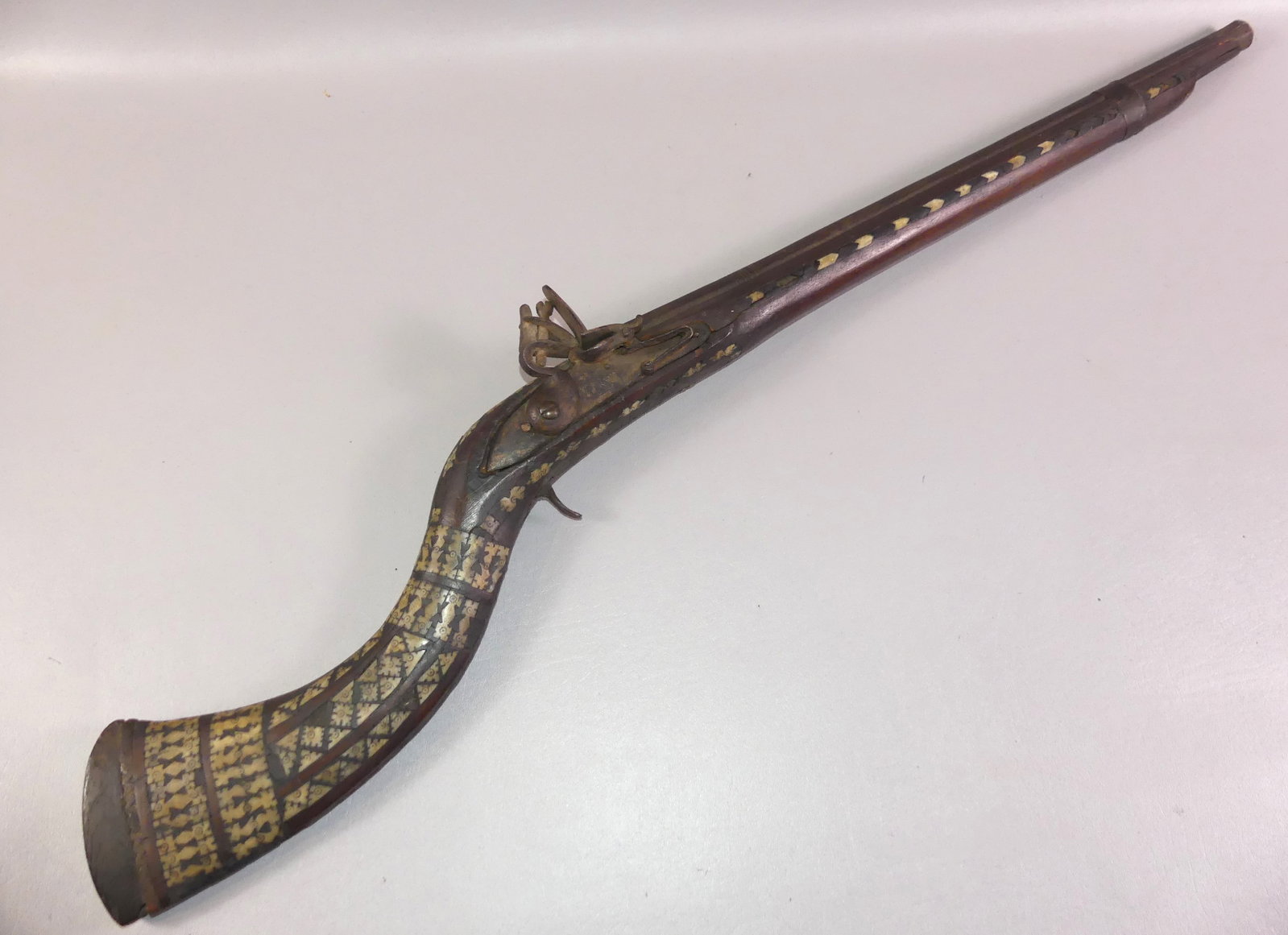 ANTIQUE CAMEL GUN: Antique North African flintlock camel gun highly inlaid with various geometric designs in bone. It is 39.5 in long with octagonal 24 in barrel. About 60 caliber. Some loss to inlay.