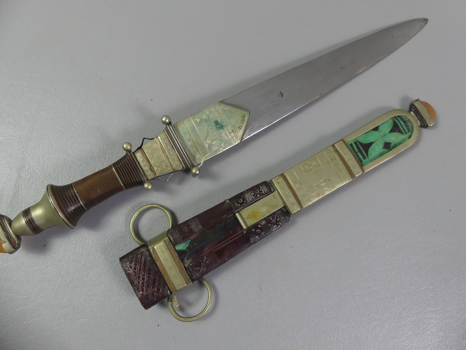 N. AFRICAN TRIBAL DAGGER: Fancy inlaid wood and metal North African tribal dagger with leather scabbard having agate and turquoise.