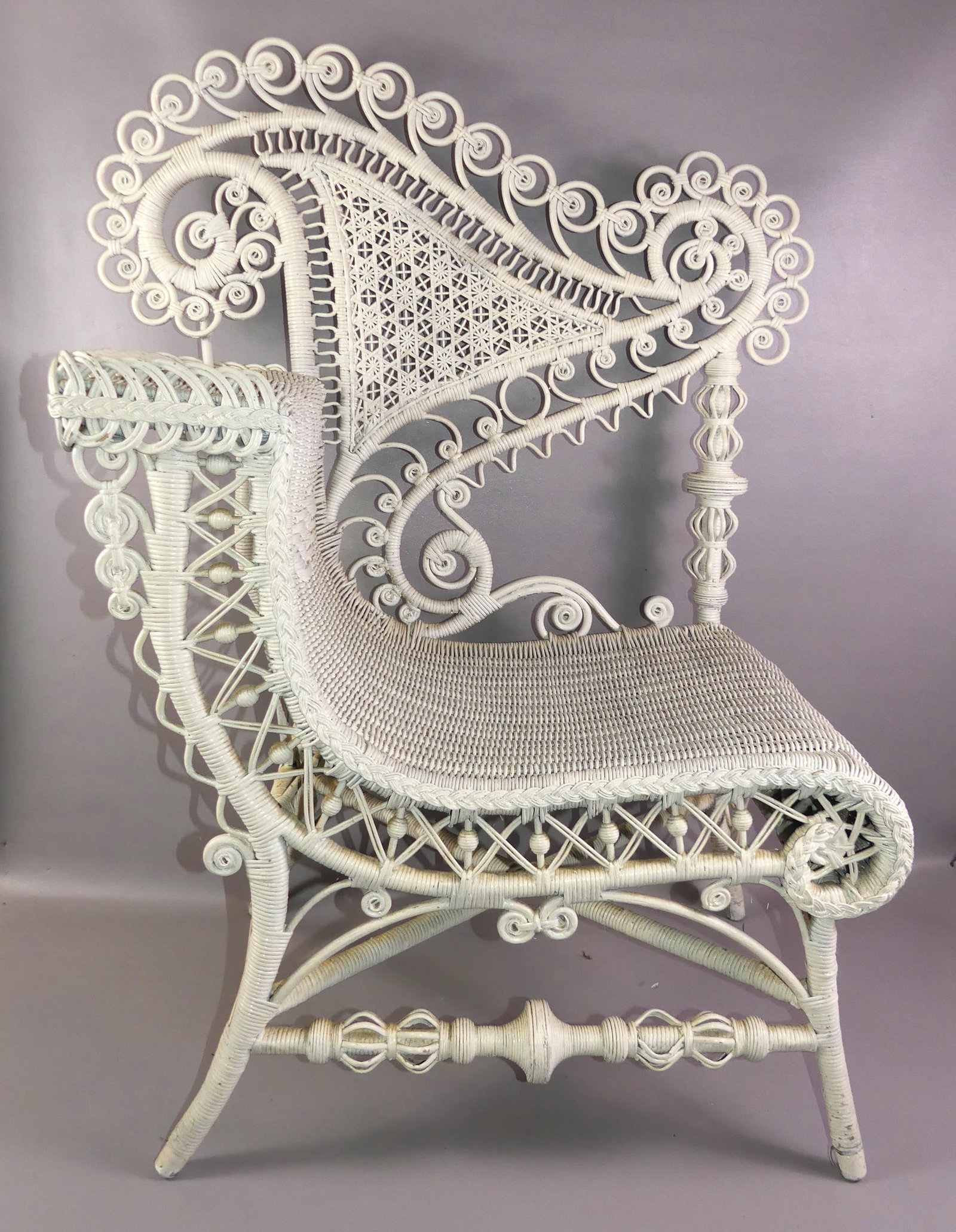 HEYWOOD WAKEFIELD WICKER PHOTO CHAIR: Antique Heywood Wakefield wicker photographer's chair painted white. Curved seat with armrest. Unsigned. 42 in high x 33 w x 19 in deep. Good condition.