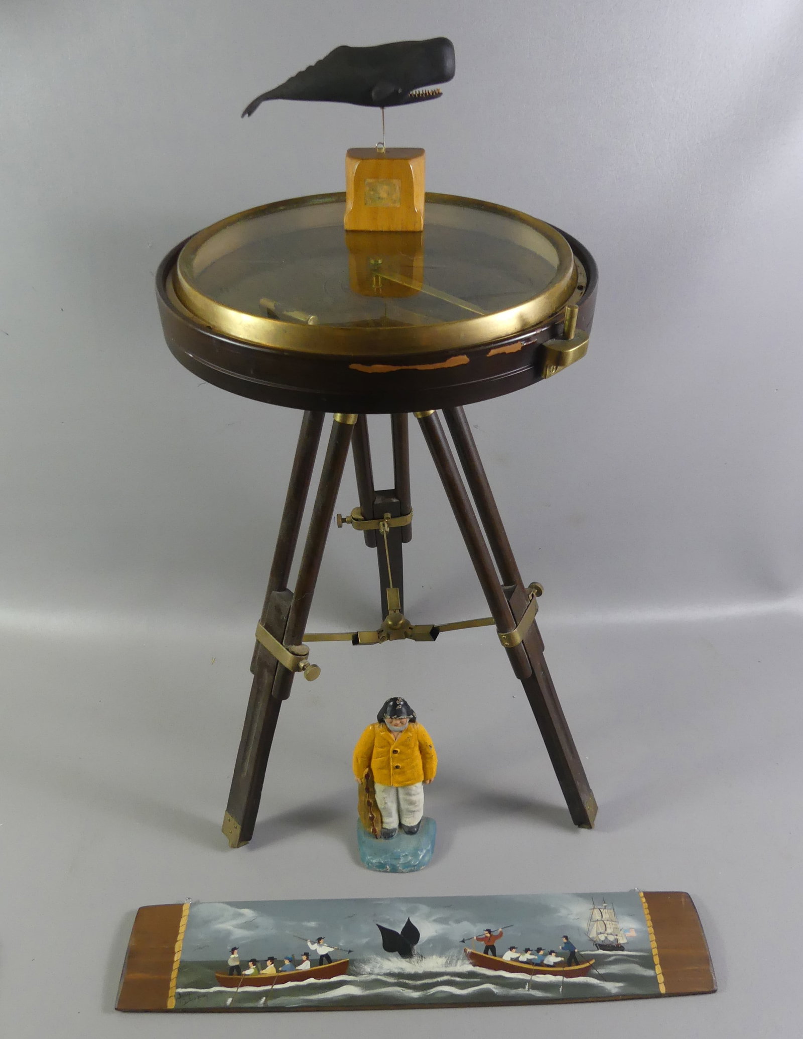 NAUTICAL LOT & COMPASS TABLE: Lot 4 maritime related items: 24 in tall x 13 in diam. Wood and brass compass table; 7 in black sperm whaling carving; 22 in painted wood plaque of whaling scene; and iron doorstop of a fisherman.
