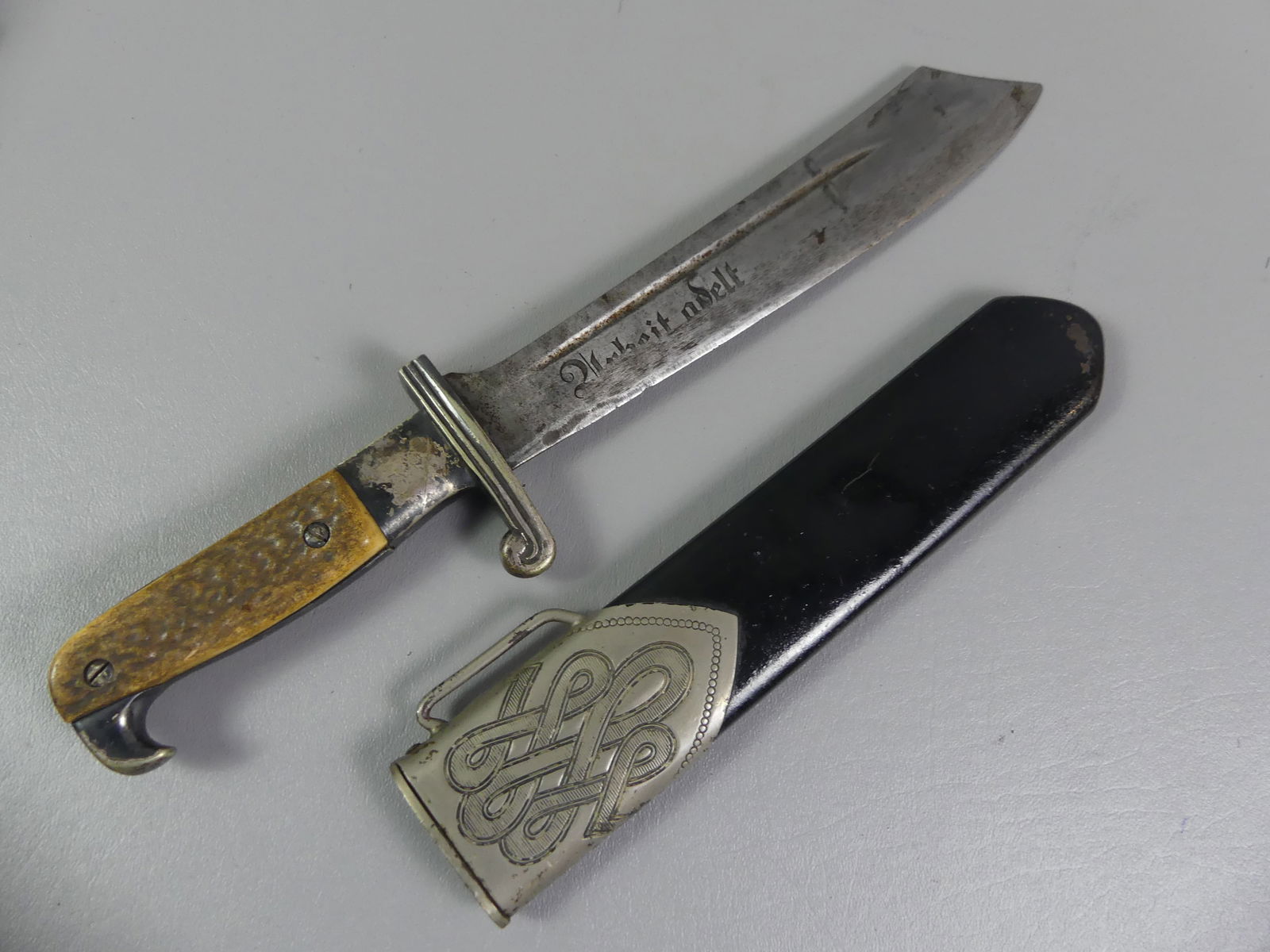 GERMAN WWII RAD HEWER KNIFE: German WWII RAD Hewer dagger with black metal scabbard with fancy silver plated designs. Signed Carl Jul. Krebs Solingen. Motto Arbeit Adelt meaning Work Ennobles. Wear to blade and motto.