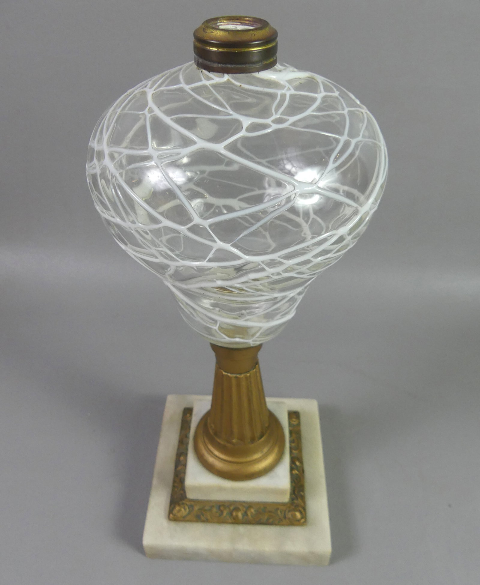 ANTIQUE BLOWN GLASS OIL LAMP: Scarce 19th century blown glass oil lamp with opal spiderweb-type decoration on the colorless font with a marble and metal base. 13 in tall. Good condition.