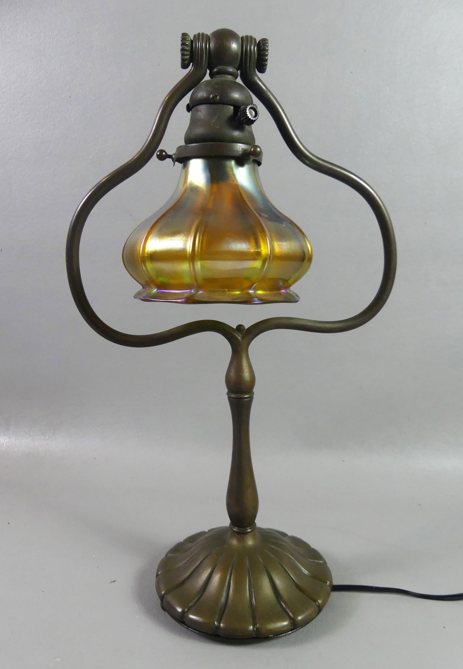 TIFFANY STUDIOS DESK LAMP: Signed Tiffany Studios NY #424 Art Nouveau bronze desk lamp with signed Quezal gold iridescent lamp shade (4 in high). Lamp base is 16.5 in tall, slighty bent harp, missing 2 ball feet.