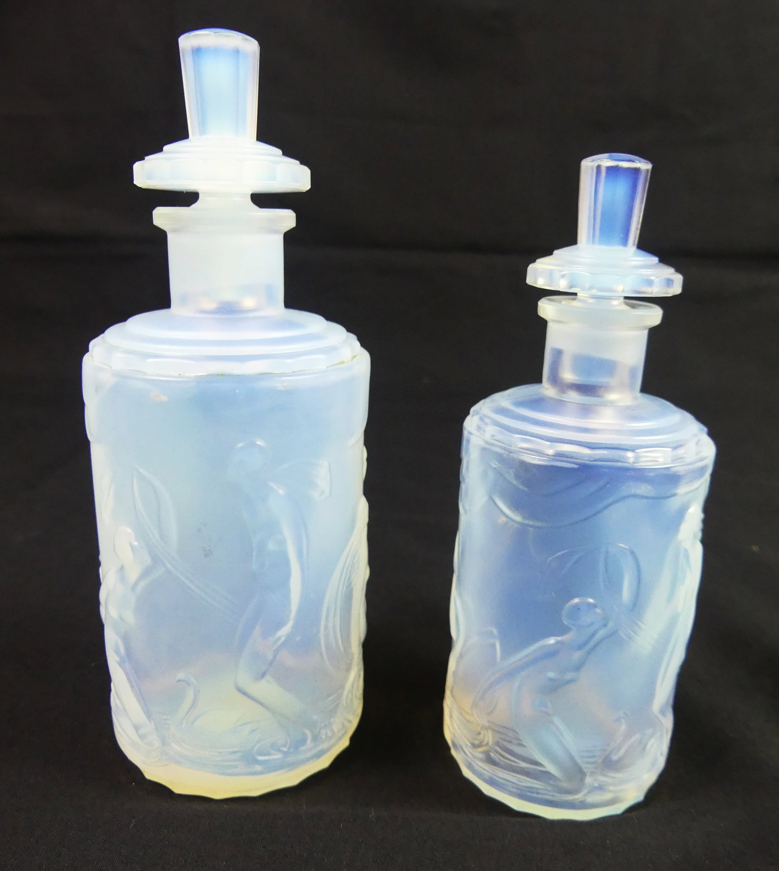 2 SABINO ART GLASS BOTTLES: Two opalescent art glass cologne bottles with nude classical embossed nymphs and swans. 6 and 5.5 in tall. Signed Sabino Paris. VG condition.