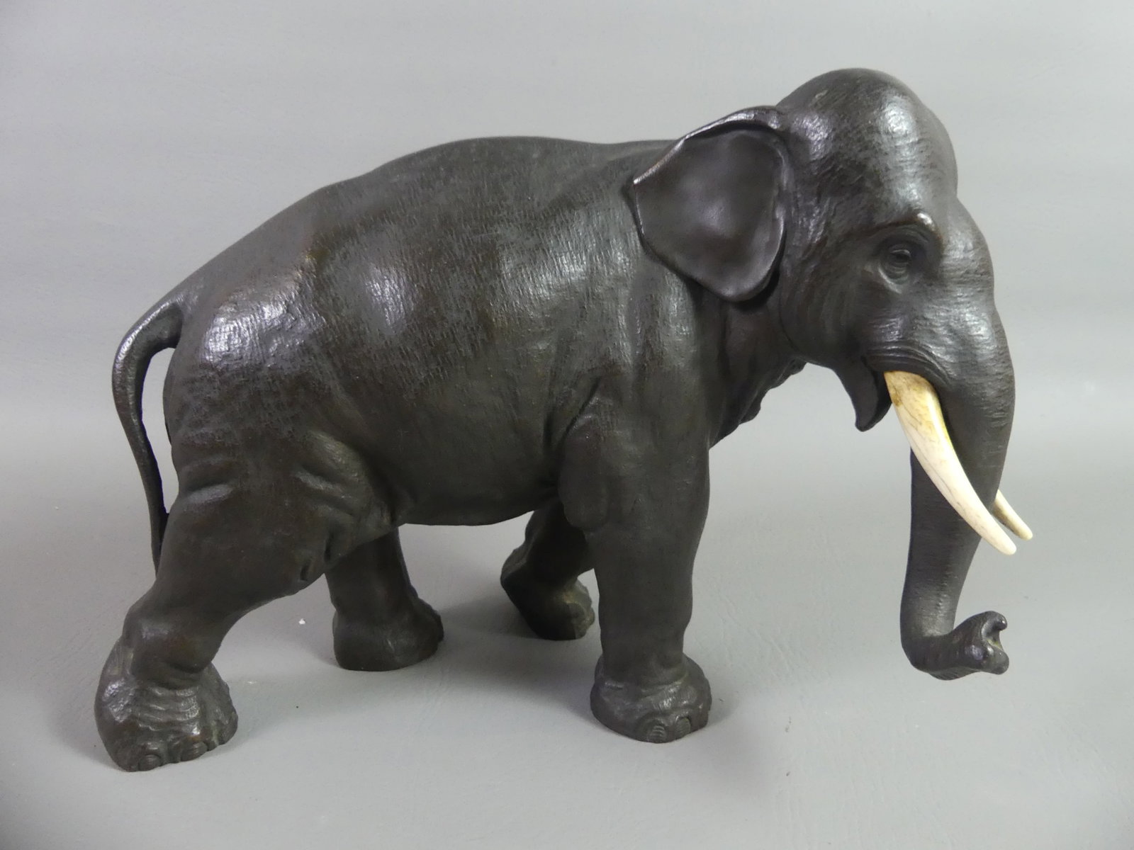 SIGNED JAPANESE BRONZE ELEPHANT: A Meiji period Japanese bronze sculpture of a standing elephant with bone tusks, 12 in long x 9.5 in high. Stamped on underside with Asian characters. Excellent condition.
