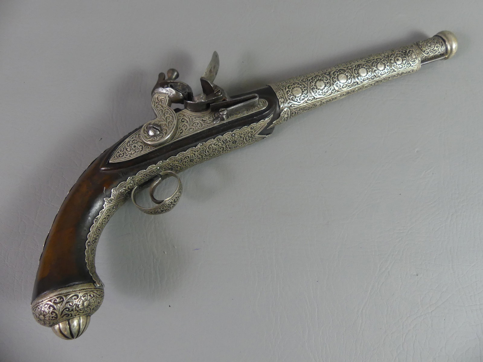 TURKISH FLINTLOCK PISTOL - SILVER INLAY: Highly decorated Turkish flintlock pistol with silver overlay designs, curved pistol grip, 16.25 in long, barrel 10.25 in. Stamped R on barrel. Good mechanics.