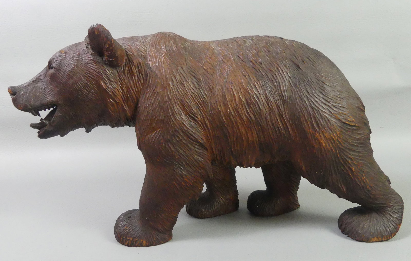 BLACK FOREST CARVED BEAR: Antique Black Forest carved wood large figure of a grizzly bear. Incised XIV on underside of foot. 16 in long x 9.5 in high. Good overall with glue repair to one foot and minor crack.