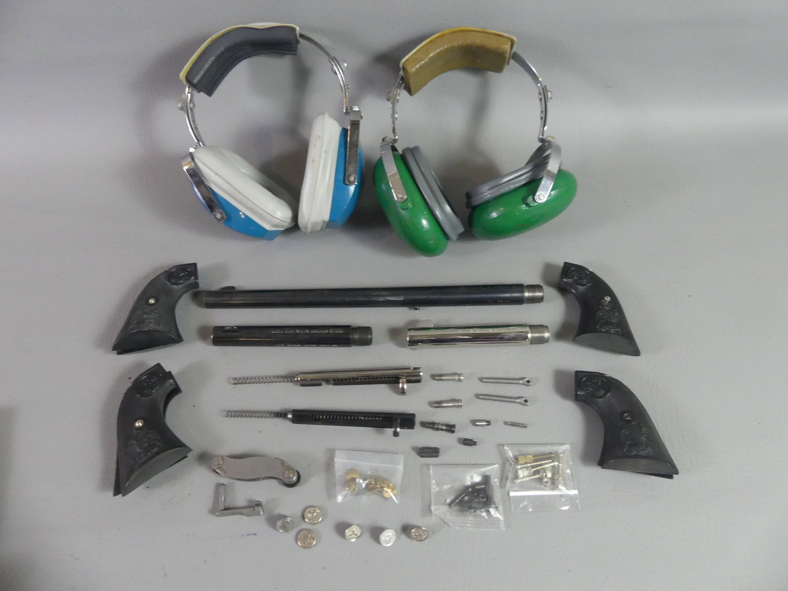 GUN PARTS & 2 EAR MUFFS: Lot assorted gun parts for Colts plus 2 sound-suppressing ear muffs, one signed Colt. Includes 12 in Buntline Special 45 barrel (black); Colt SAA 45 Army 5.5 in barrel; Colt SAA 45 Army 4.75 in barrel