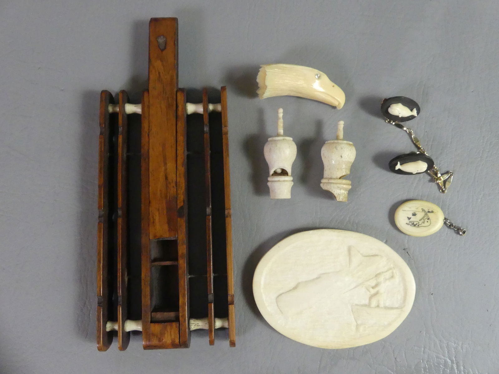 ASSORTED CARVED WHALEBONE LOT: Lot of assorted carved whalebone items: 4.25 in oval plaque with man harpooning whale; 2 sailor made whistles; 2.5 in eagle head; 7 in long whale bone and rosewood fishing rig with sliding compartment