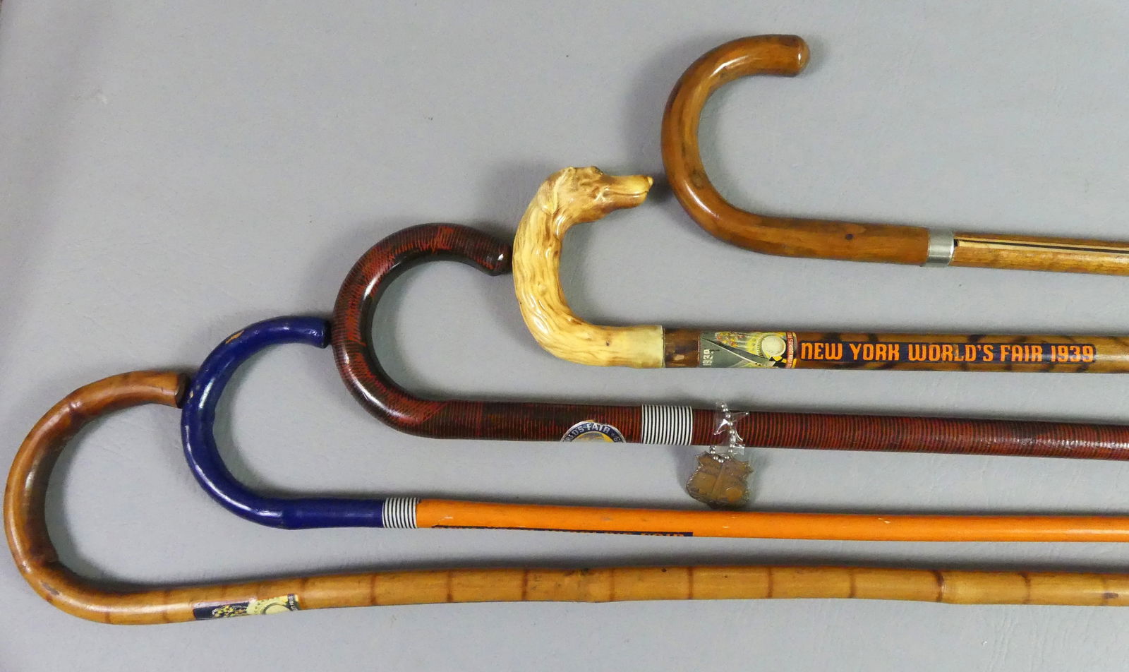 5 NEW YORK WORLD FAIR CANES: Lot 5 souvenir canes from the New York World's Fair in 1939/40. All have shepherd hook handles to 38.5 in long. Includes one with printed fabric pull-out map of the fair; plastic dog head; 1940 bamboo