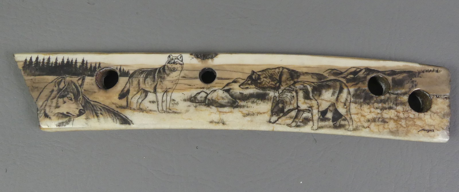SCRIMSHAW WALRUS SLED RUNNER: Fossilized Inuit walrus bone sled runner with color scrimshaw of 4 wolves signed Andhi. 10.5 x 1.75 inches, weighs 10.45 oz.