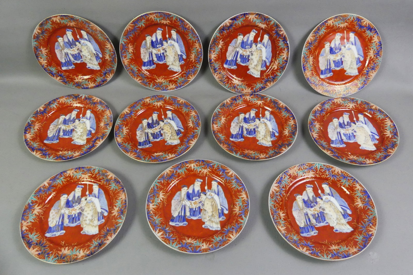 11 JAPANESE KUTANI PLATES - SCHOLARS: Set of 11 unusual antique Japanese Kutani plates, each having 4 scholars examining a scroll in center. Signed. Meiji Period. 8.5 in diameter. 9 in good condition, 2 have minor rim flakes.