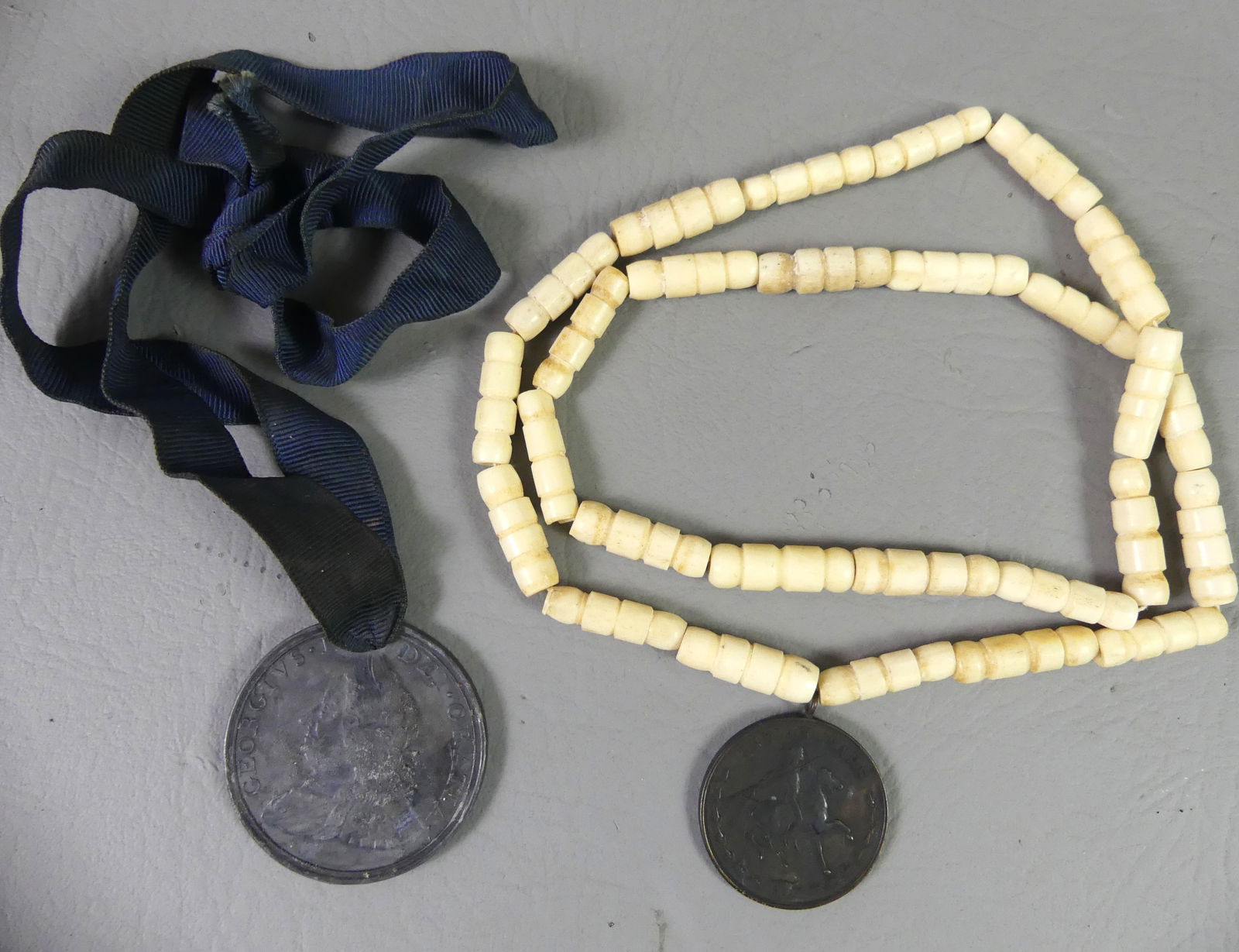2 MEDALS: INDIAN WARS & GEORGE II: Lot of 2 medals: Bronze 35.43 mm medal, US Army for Service during the Indian Wars (bone necklace); and George II 49.6mm medal dated 1757(?) with blue ribbon.