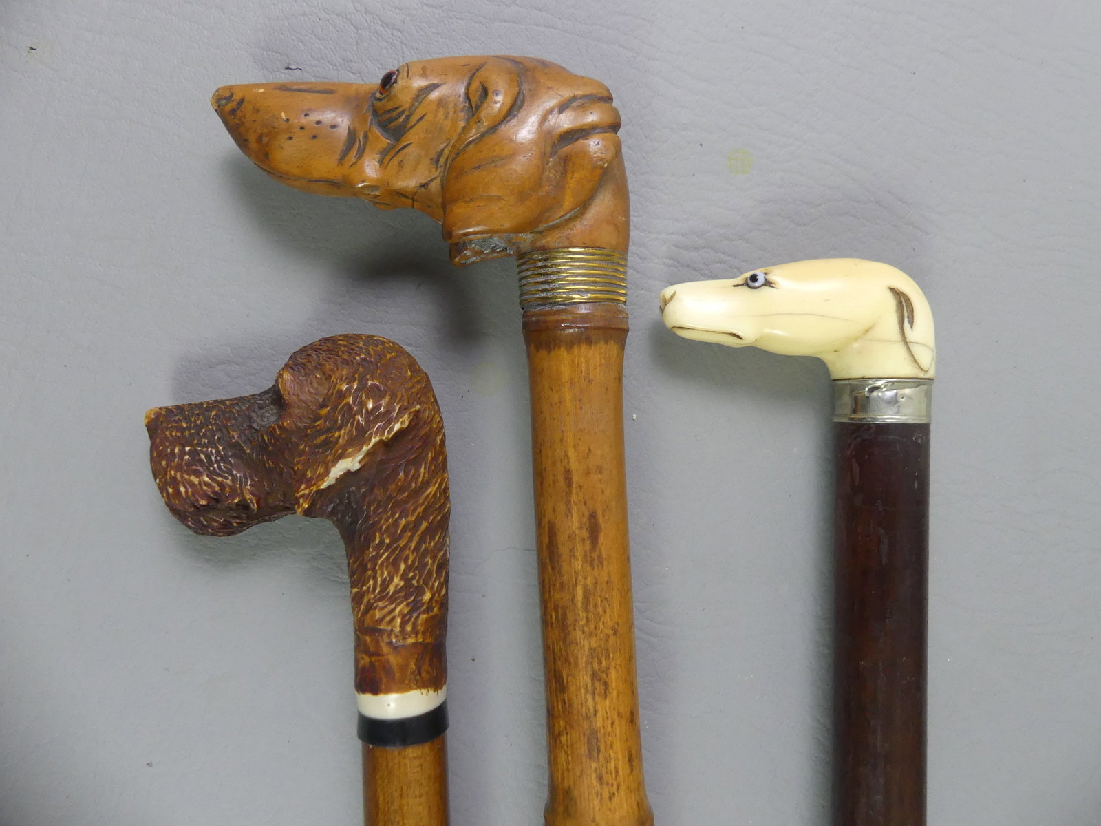 3 DOG HEAD CANES: Lot of 3 dog-related canes to 36 in: Carved and stained bone Airedale Terrier; Carved bone greyhound head (missing one eye); and carved wood Dachshund with glass eyes and bamboo shaft.
