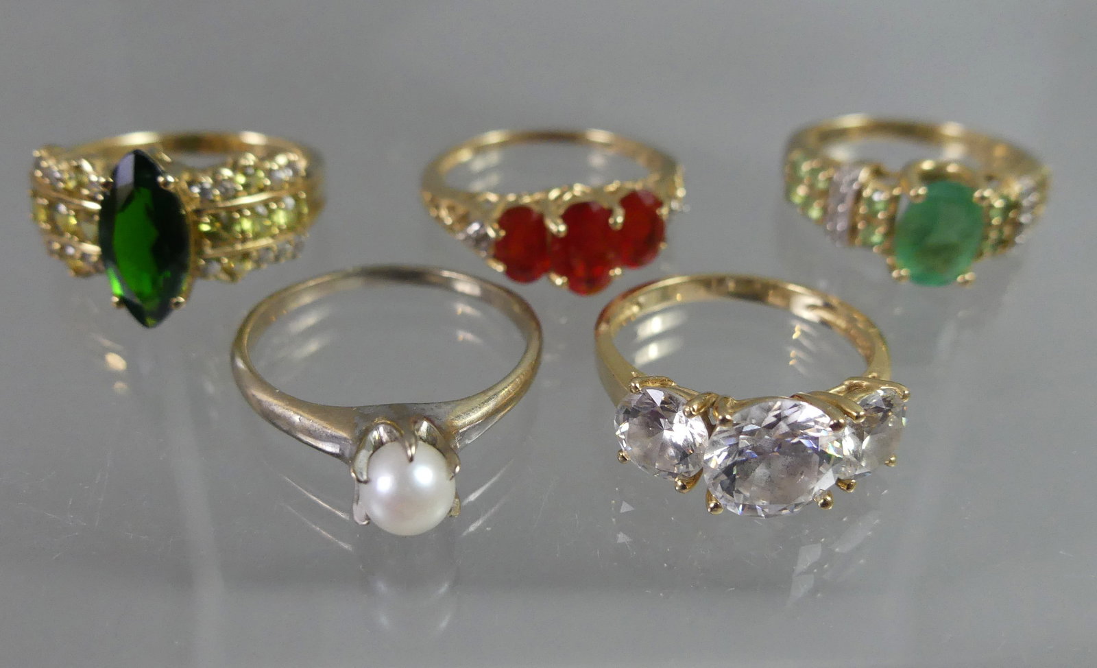 5 GEMSTONE RINGS 10-14K GOLD: Lot 5 gemstone rings: 10k gold with pearl (size 7.5); 10k green garnet (size 7); 14k emerald (size 6); 14k triple CZ; 14k triple ruby (6.5 size). Total weight 9.8 dwt. NOTE: We can ship this item in-h