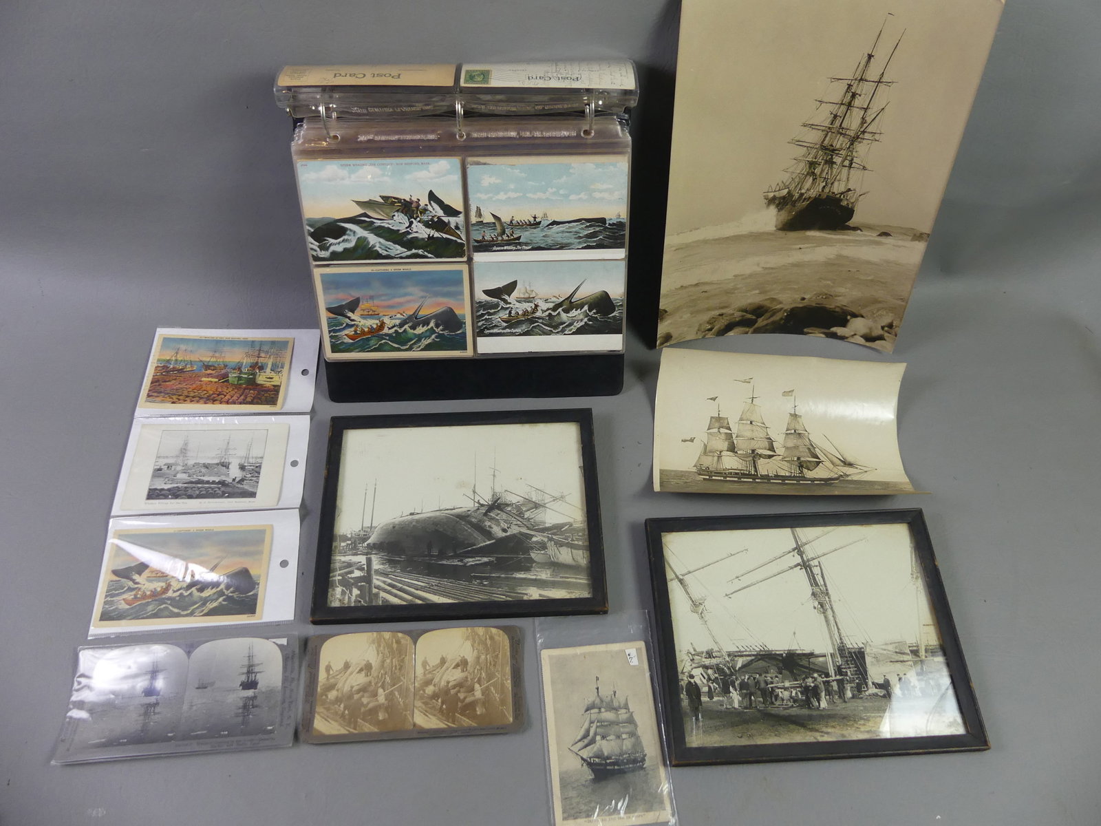 100 WHALING POSTCARDS & PHOTOS: Lot o whaling related ephemera: Postcard album with approximately 100 old postcards depicting whales, whaling ships, beached whales, whaling scenes, etc; 2 stereocards; 2 framed photos of men working