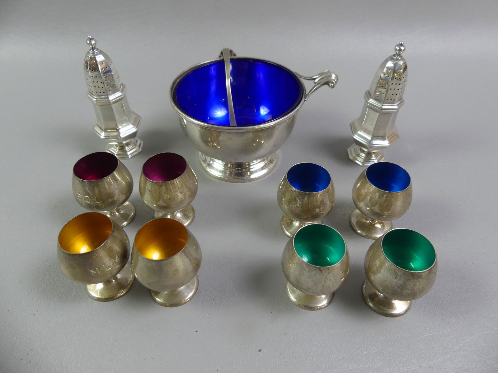 12 PIECES STERLING SILVER TABLEWARE: Lot of 12 pieces sterling silver: Set 8 Gorham cordials with colored enamel interiors, 2.25 in (light monograms); bowl with ladle and cobalt glass insert, 5 in diam; pair salt and pepper shakers.