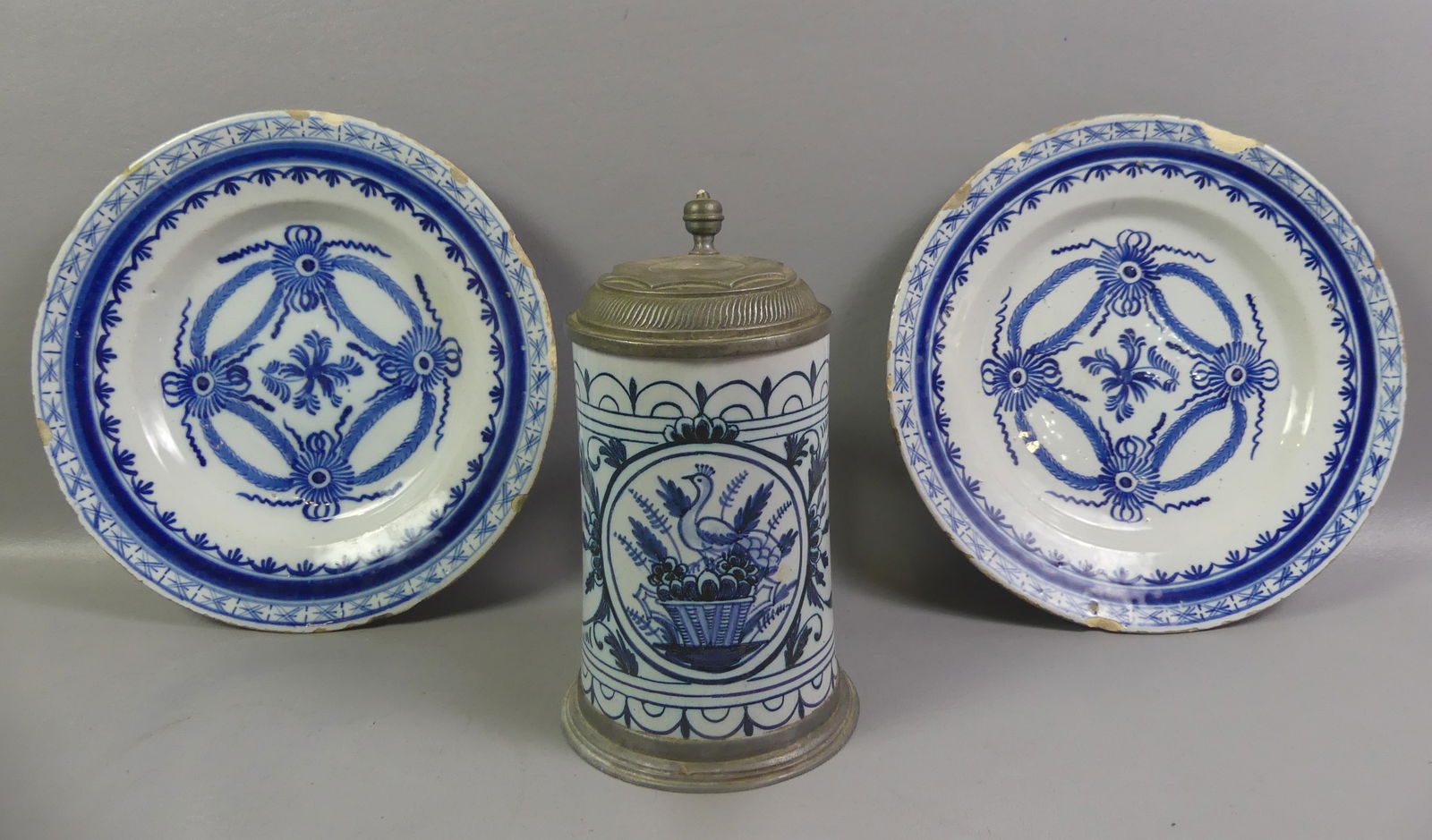 EARLY FAIENCE ITEMS: PLATES & STEIN: Lot of 3 continental faience items circa 1700's: Pair of 10 in tin-glazed blue and white plates (rim chips); and 8 in tall lidded stein with bird and flower medallion signed ME on base, good