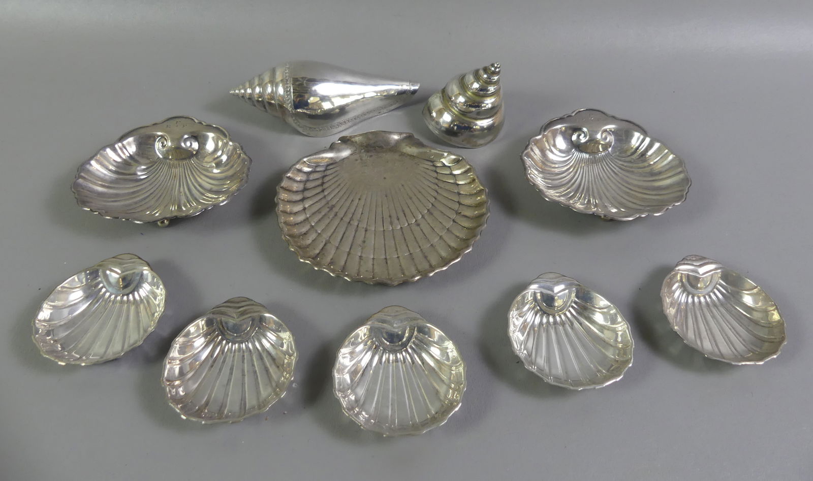 10 STERLING SEASHELL FORM ITEMS: Lot of sterling silver items in seashell form: Set 5 nut dishes, 3.25 in; two .900 silver spiral shells; and 3 other seashell items to 5.75 in long. 19.8 ozt. NOTE: We can ship this item in-house.