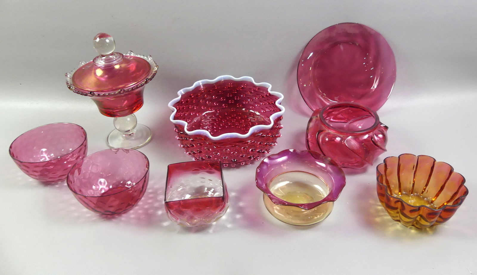 9 PCS AMBERINA & CRANBERRY ART GLASS: Lot 9 pieces of old art glass: 9 x 3.5 in hobnail bowl with opalescent scalloped rim; 5.5 in fuschia amberina bowl; pair 5 in thumbprint bowls; 9.5 in covered and footed compote, etc. All very good