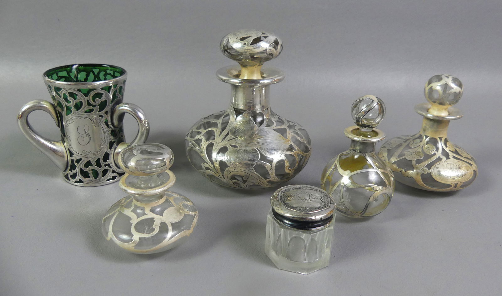 6 SILVER OVERLAY GLASS VANITY ITEMS: Lot 6 antique silver overlay on glass vanity items including perfume bottles to 5 in tall, small jar with sterling lid, and a 3-handled small green vase (internal cracks). Other items in good